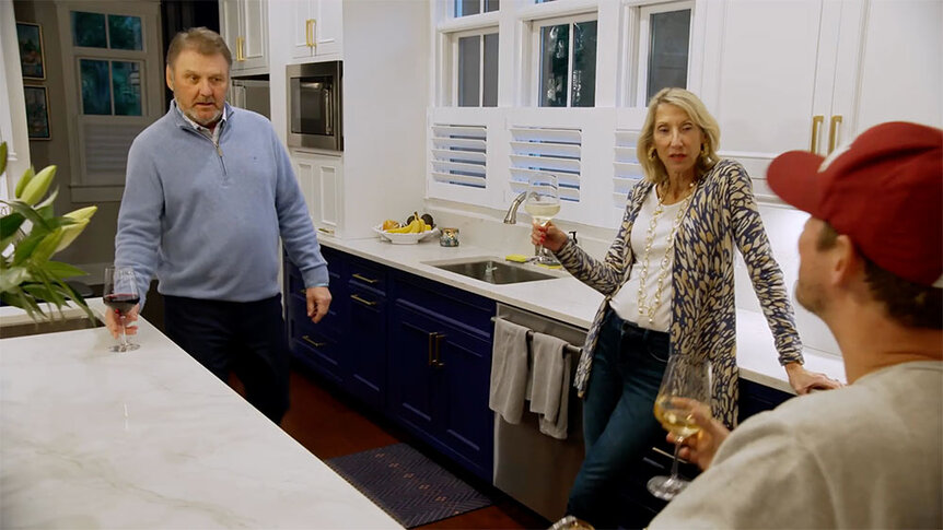 Austen Kroll and his parents talking while holding wine in his parent's kitchen.