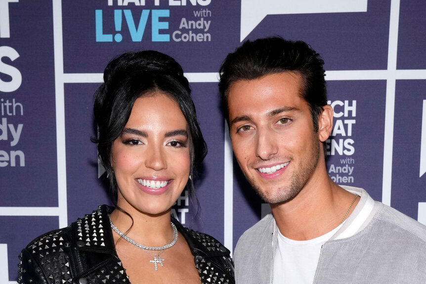 Danielle Olivera and Joe Bradley posing together on a step and repeat at the Watch What Happens Live Studios.