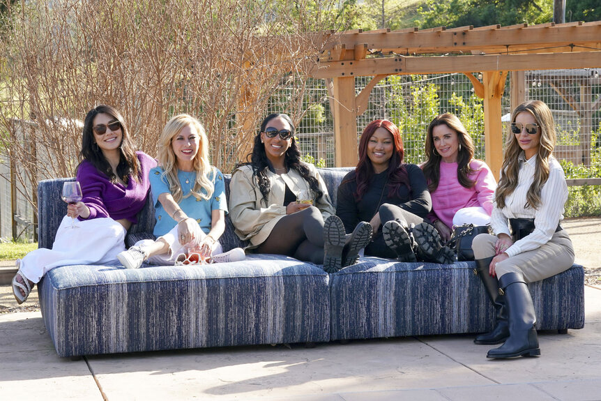 Crystal Kung-Minkoff, Sutton Stracke, Annemarie Wiley, Garcelle Beauvais, Kyle Richards, and Dorit Kemsley sitting together and smiling on a couch.