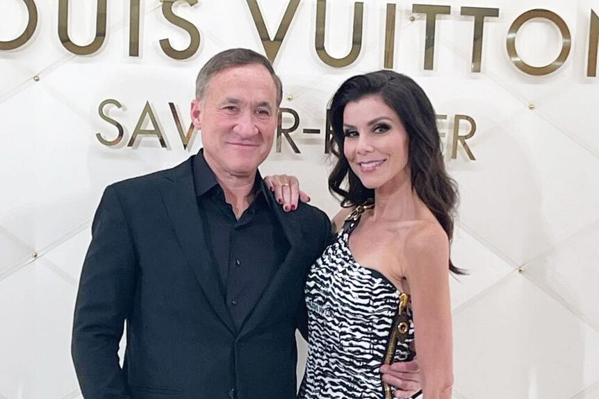 Heather Dubrow and Terry Dubrow posing in front of a step and repeat together.