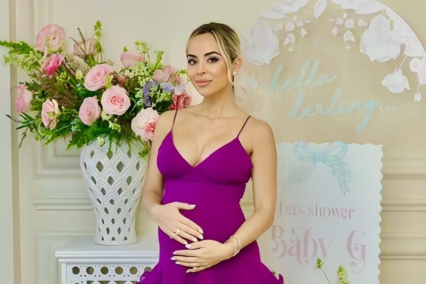 Nicole Martin wearing a purple dress holding her pregnancy bump.