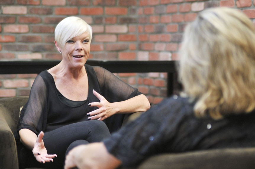 Tabatha Coffey sitting and talking in front of a brick wall.