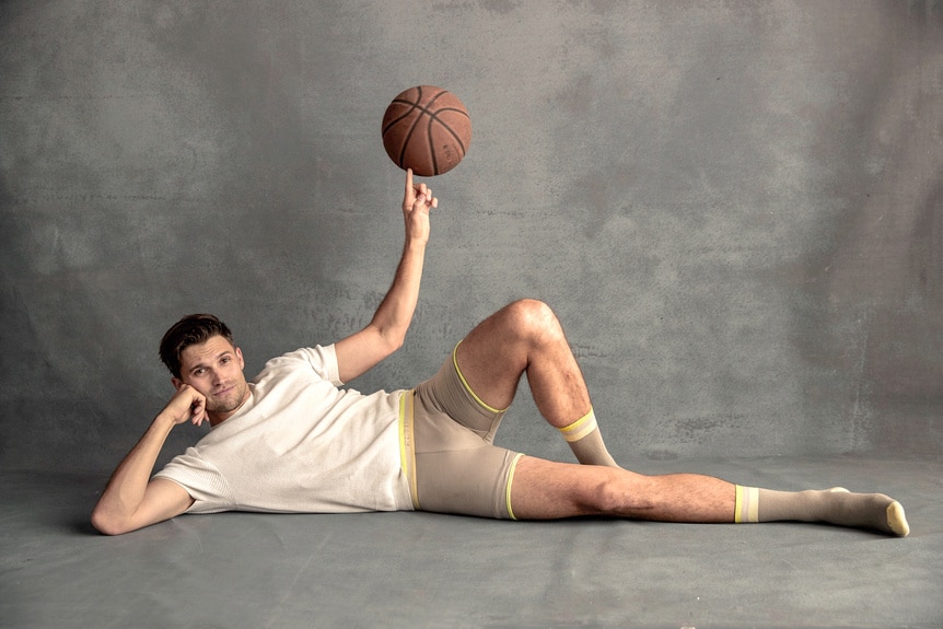 Tom Schwartz lying down and balancing a basketball on his finger