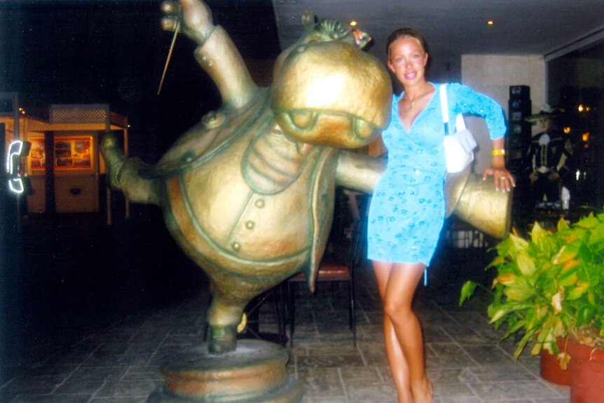 Lisa Hochstein posing in a blue mini dress with a statue.