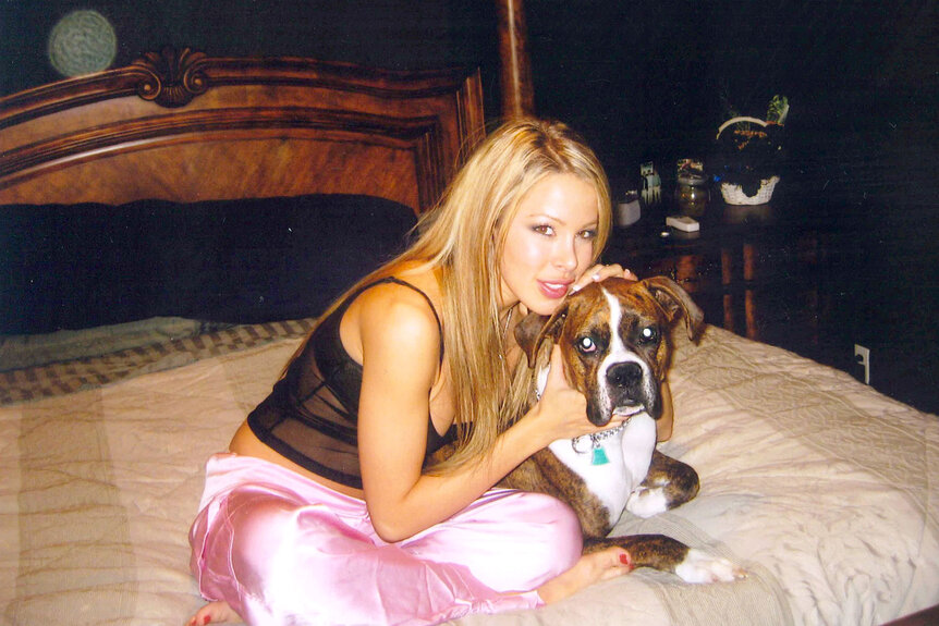 Lisa Hochstein sitting on a bed with a dog.