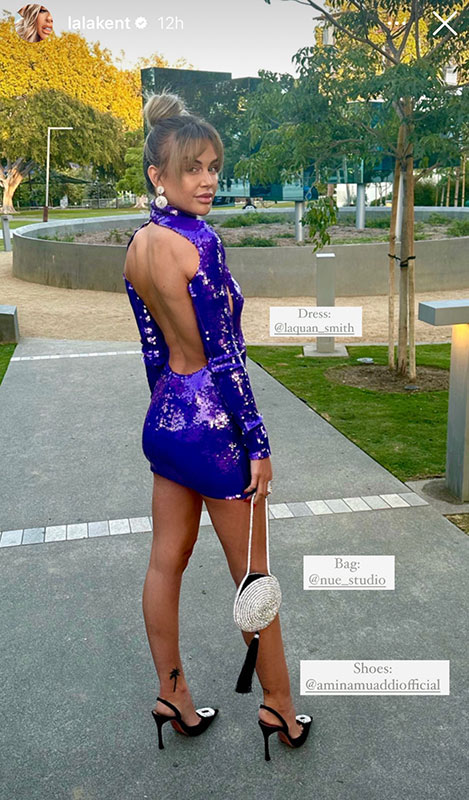 Lala standing in a driveway posing in a backless, purple, sequins mini dress with an updo.