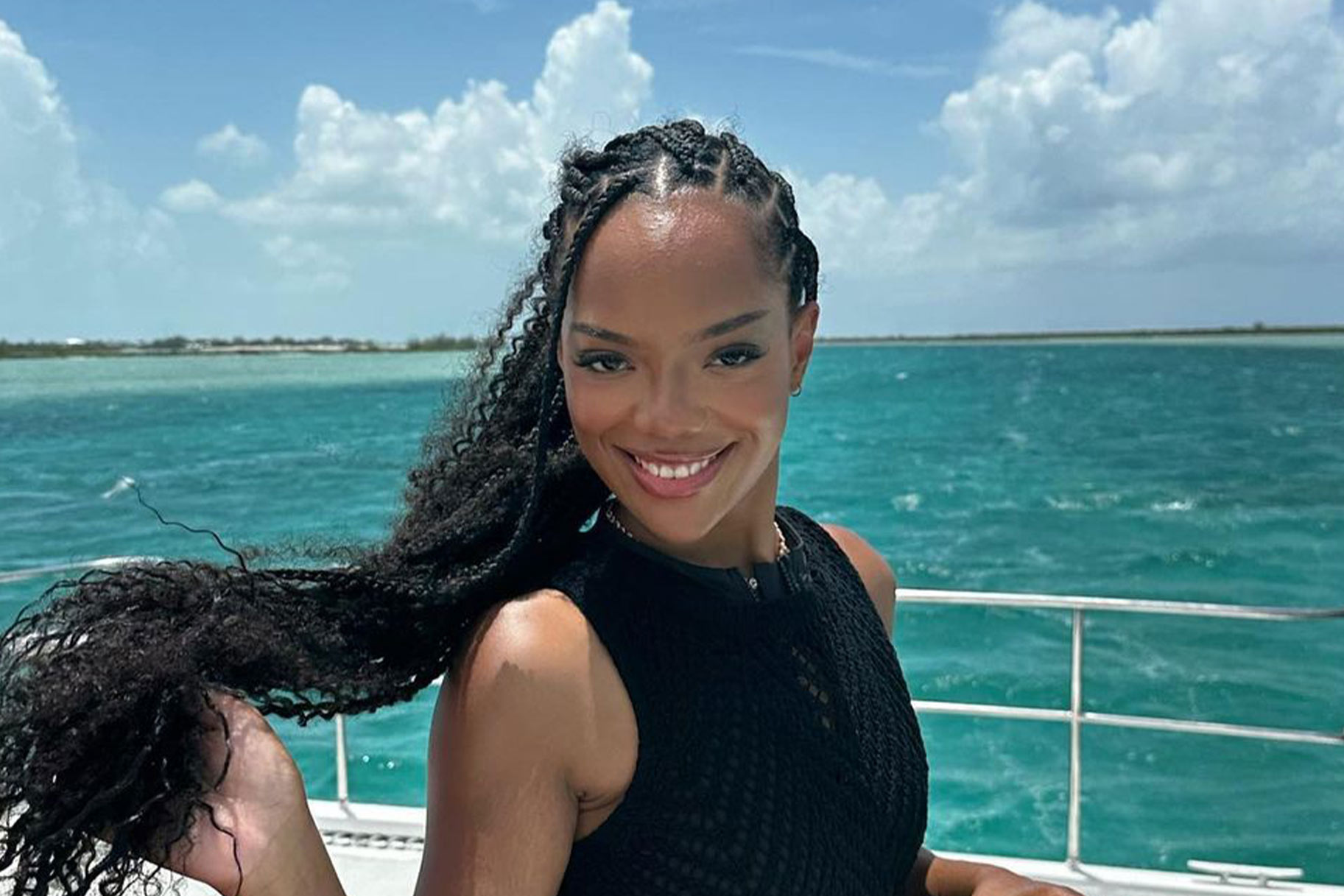 Riley Burruss with braids and a black outfit smiling on a boat.
