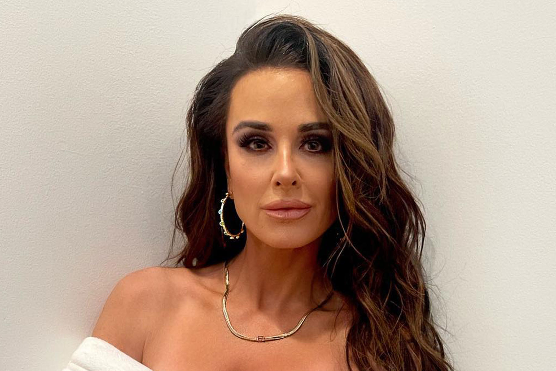 Kyle Richards posing in front of a white wall in a robe.