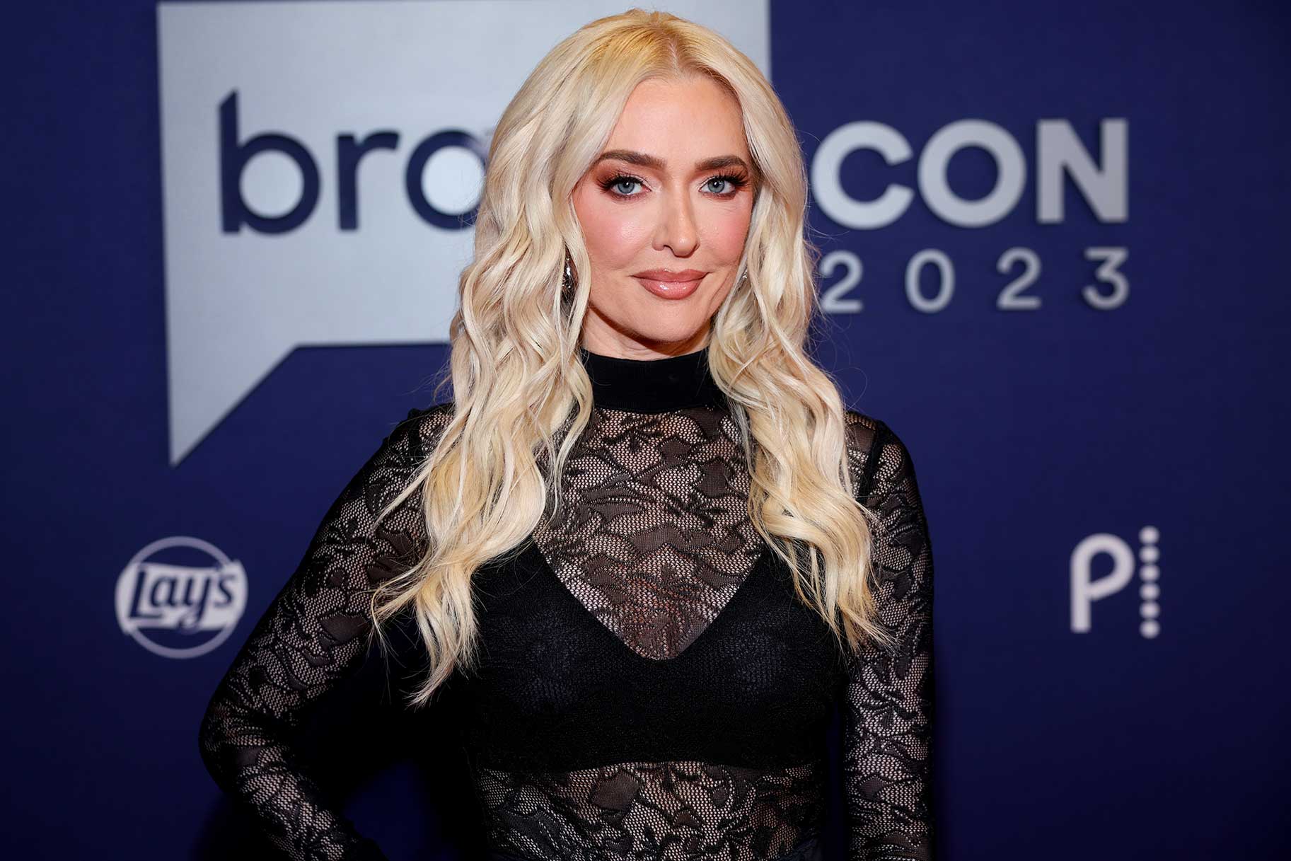 A close up of Erika Jayne wearing an all black lace top and posing for the camera.