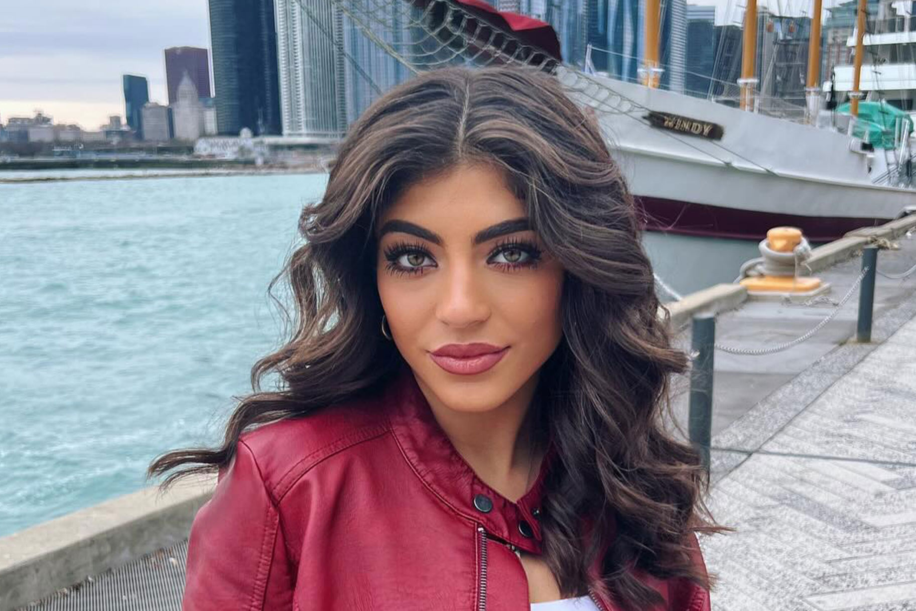 Milania Giudice posing on a pier in front of a boat.