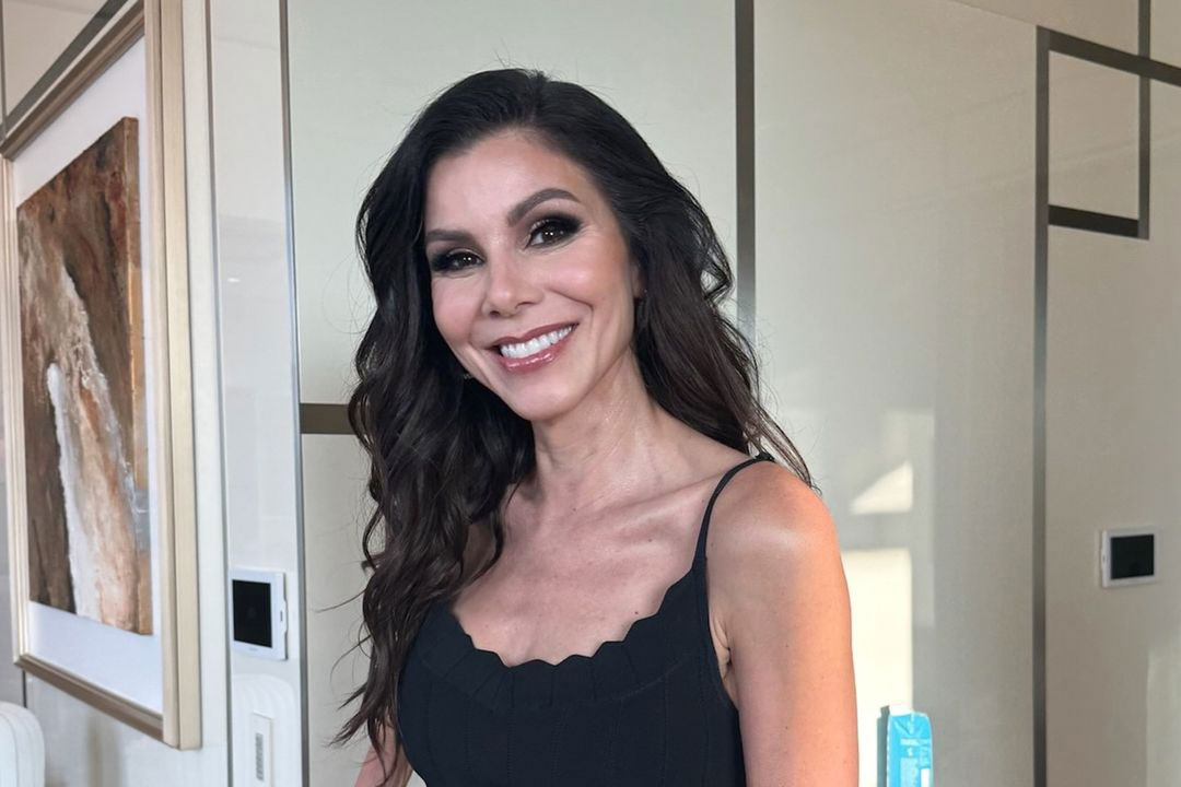 Heather Dubrow smiling and wearing a black spaghetti strap dress.
