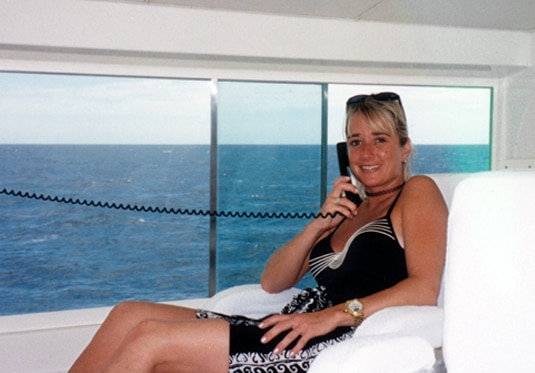 Kim sitting on a yacht, talking on a cell phone.