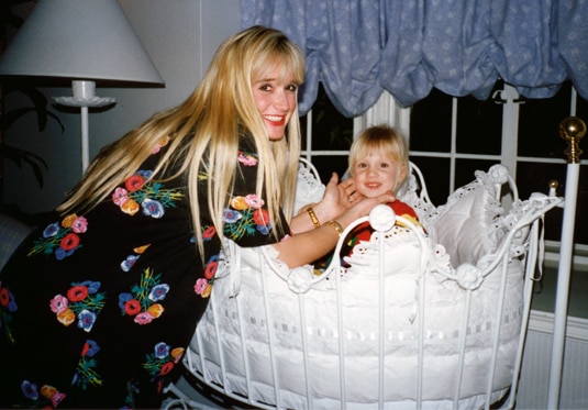 Kim Richards playing with a baby in a bassinet.