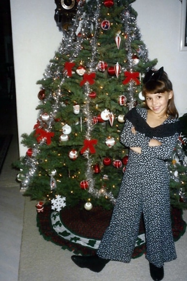 Scheana Shay poses in front of a Christmas tree as a young girl.
