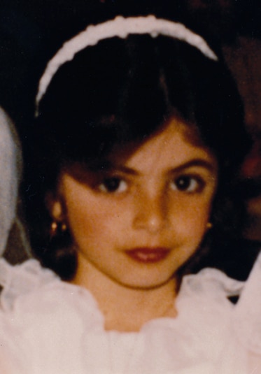 Young Larsa Pippen posing in a white headband and white dress.
