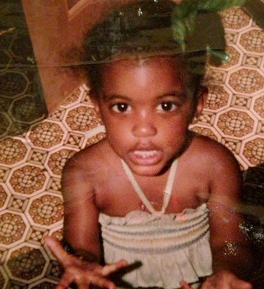 Porsha Williams as a young girl sitting on a floor looking expressive