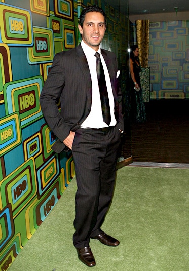 Mauricio Umansky smiling in a suit in front of a patterned wall.