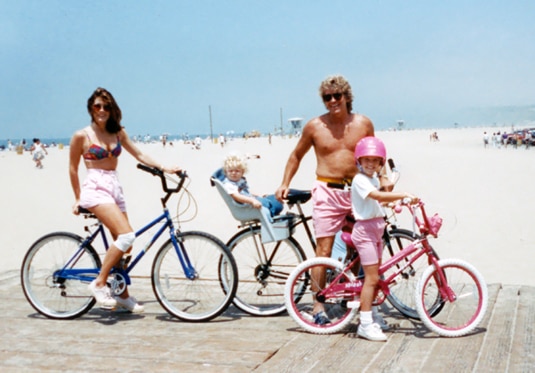 Lisa, Ken, and their two children posed next to the beach while on bikes.
