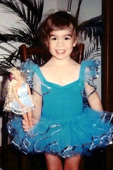 Katie Maloney holds a doll while wearing a tutu.