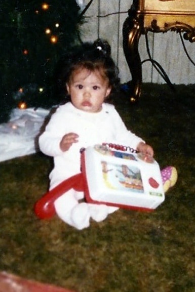Scheana Shay plays with a toy underneath the Christmas tree as a baby.