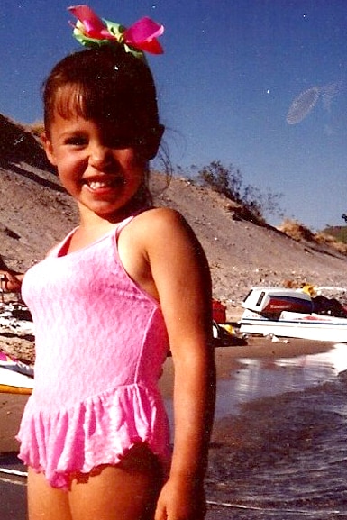 Scheana Shay wears a pink bathing suit in front of boats as a young girl.