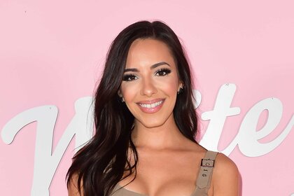 Charli Burnett smiles in a nude colored dress in front of a step and repeat in Los Angeles.