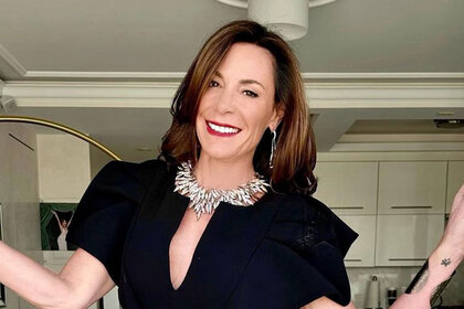 Luann posing in a black jumpsuit and chunky necklace.