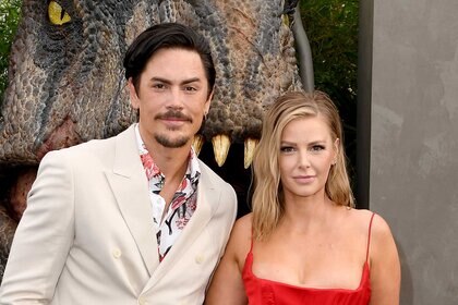 Tom Sandoval and Ariana Madix pose together in front of a dinosaur at the Jurassic World Dominion premiere