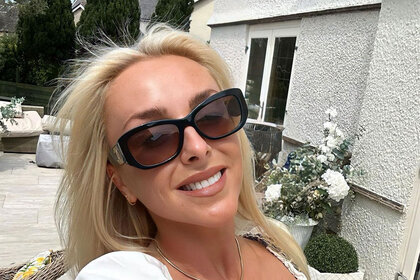 Courtney Veale takes a smiling selfie with black sunglasses in a white dress.