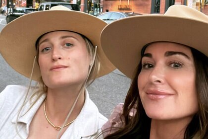 Kyle Richards and Whitney White pose together wearing wide brimmed, camel toned, hats.