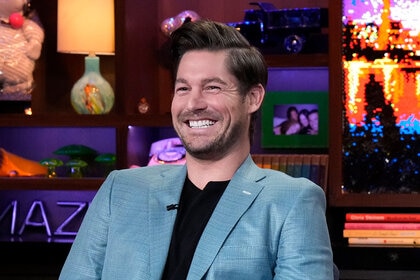 Craig smiling in a blue suit jacket and black shirt at the Watch What Happens Live clubhouse.
