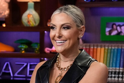 Gina smiling in a black leather vest at the Watch What Happens Live clubhouse.