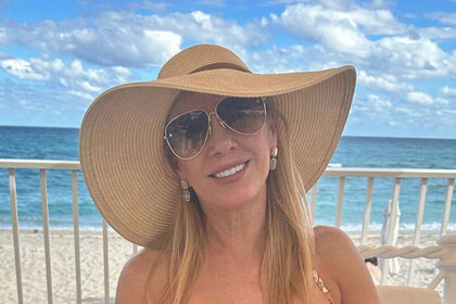 Ramona wearing a sun hat and sunglasses on the beach.