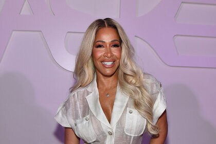 Sheree smiling in a white look with blonde hair at an event.