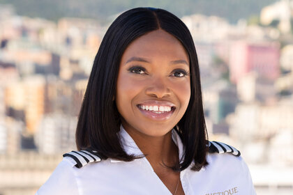 Tumi smiling in her uniform in front of the coastline.