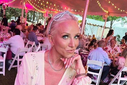 Margaret Josephs wearing a crystal-studded headband and white, v-cut, maxi dress at an event.