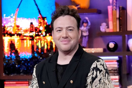 Kyle Viljoen wears a black blazer with feather sleeves while a guest on WWHL.