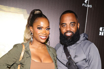 Kandi Burruss and Todd Tucker pose together in casual looks in front of a step and repeat.