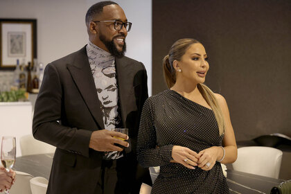 Larsa Pippen and Marcus Jordan laughing next to each other dressed in cocktail attire.