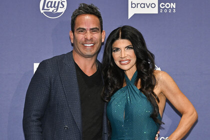 Teresa Giudice and Louie Ruelas pose in front of a step and repeat at BravoCon 2023.