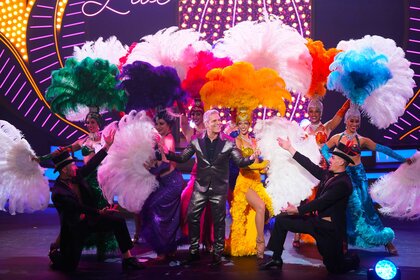 Andy Cohen appears with dancers wearing dance colorful dance outfits during The Bravos at BravoCon 2023.