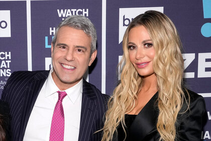 Andy Cohen and Dorit Kemsley pose together in front of a step and repeat.