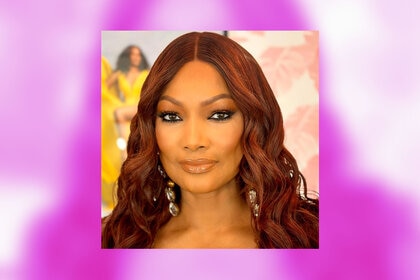 Garcelle Beauvais posing in her glam room overlaid onto a pink background.