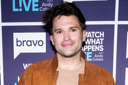Tom Schwartz wearing an earth-toned outfit in front of a step and repeat at the Watch What Happens Live clubhouse in New York City.