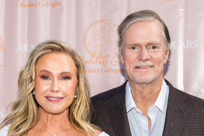 Kathy Hilton and Rick Hilton pose together in front of a step and repeat.