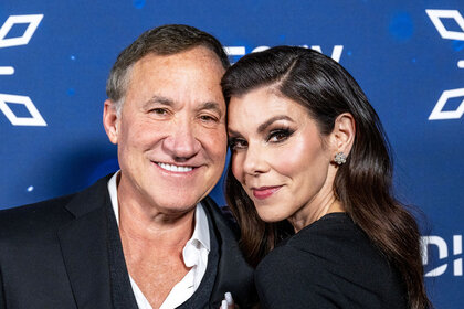 Heather Dubrow and Terry Dubrow posing together in front of a step and repeat.