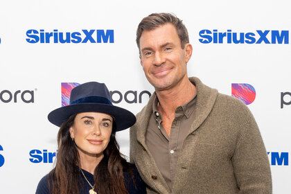 Kyle Richards and Jeff Lewis smiling next to each other in front of a step and repeat.
