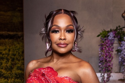 Phaedra Parks wears a beaded red and pink gown with floral embellishments in front of a vineyard-inspired set.