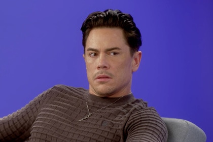 Tom Sandoval wearing a brown sweater in front of a purple backdrop