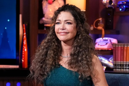 Denise Richards wearing a greed dress with curly brunette hair at WWHL